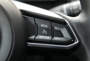 Close-up of a car steering wheel control panel showing Adaptive Cruise Control buttons labeled "Mode," "Off/Can," "Set," and "Res/+"