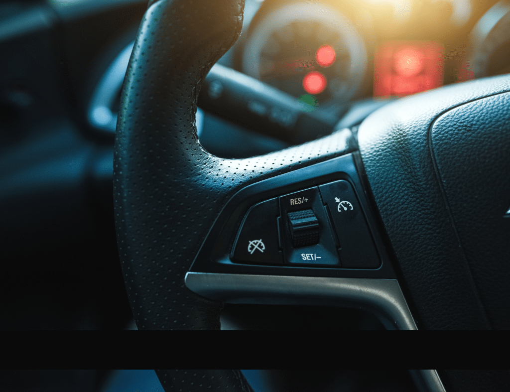 Steering wheel with Adaptive Cruise Control controls featuring "Set" and "Res/+" buttons illuminated, with a modern dashboard in the background